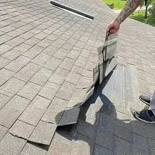Roofer looking underneath some shingles
